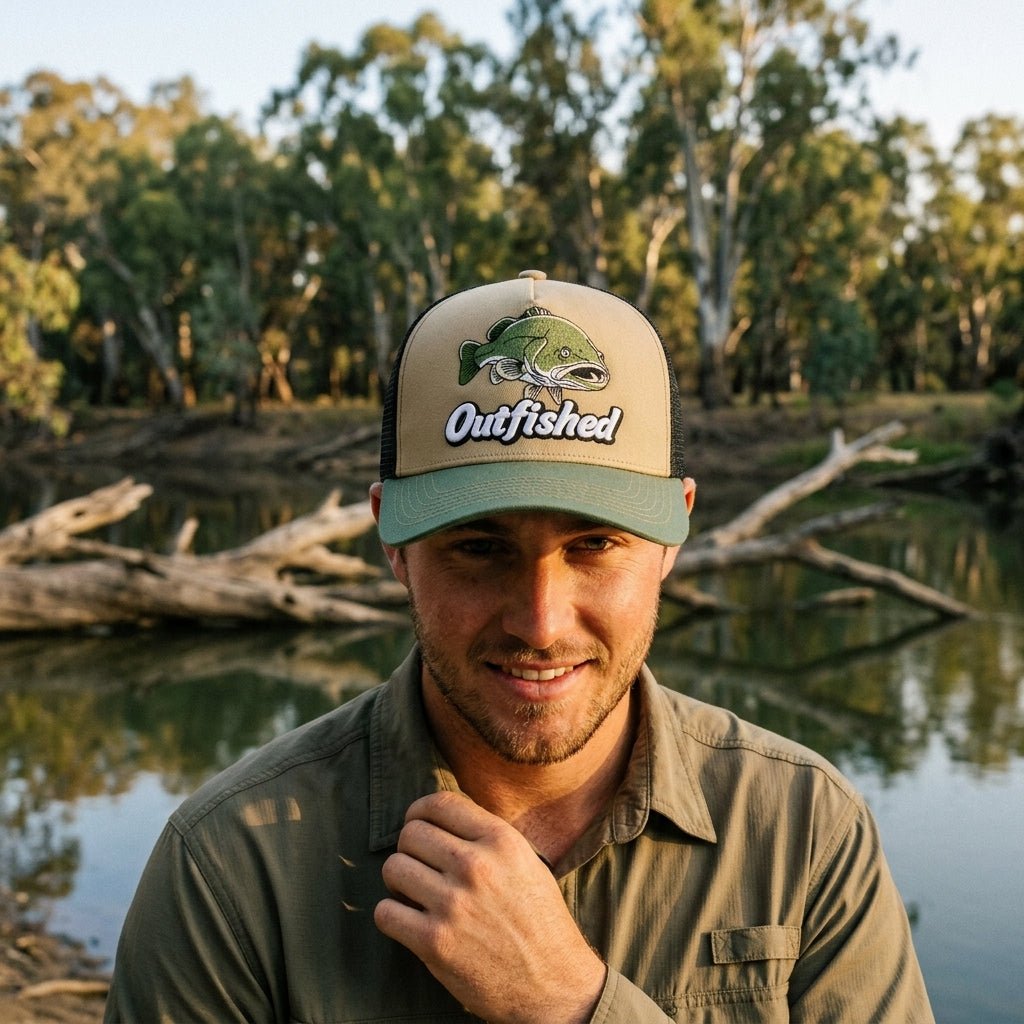 Man wearing The Goodoo Murray cod fishing cap beside an inland Australian river