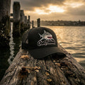 The Noah bull shark fishing trucker cap on weathered jetty piling at sunset